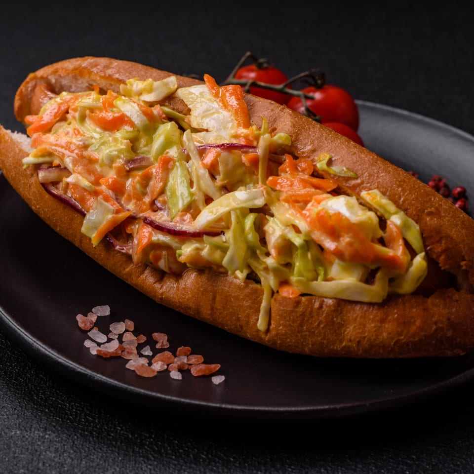 A Fitchy's Hoagy sandwich filled with coleslaw, carrots, and red onions on a dark plate.
