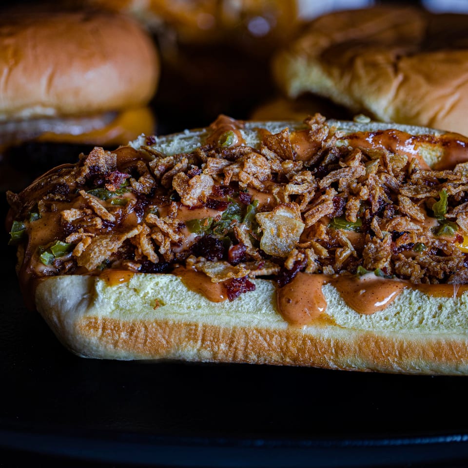 A Fitchy's Hoagy sandwich, topped with crispy fried onions, sauce, and green peppers.